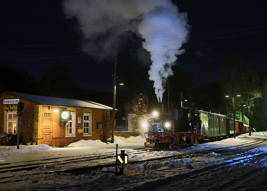 Dampflok 99 1568-7 bei Nacht am verschneiten Bahnhof Schmalzgrube mit aufsteigendem Dampf und warmem Bahnhofslicht