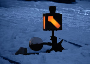 Historische Weichenlaterne leuchtet orange im Dämmerlicht über schneebedeckten Gleisen der Preßnitztalbahn